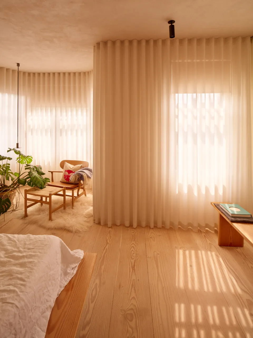 Bedroom with full-height linen curtains and a pale timber floor