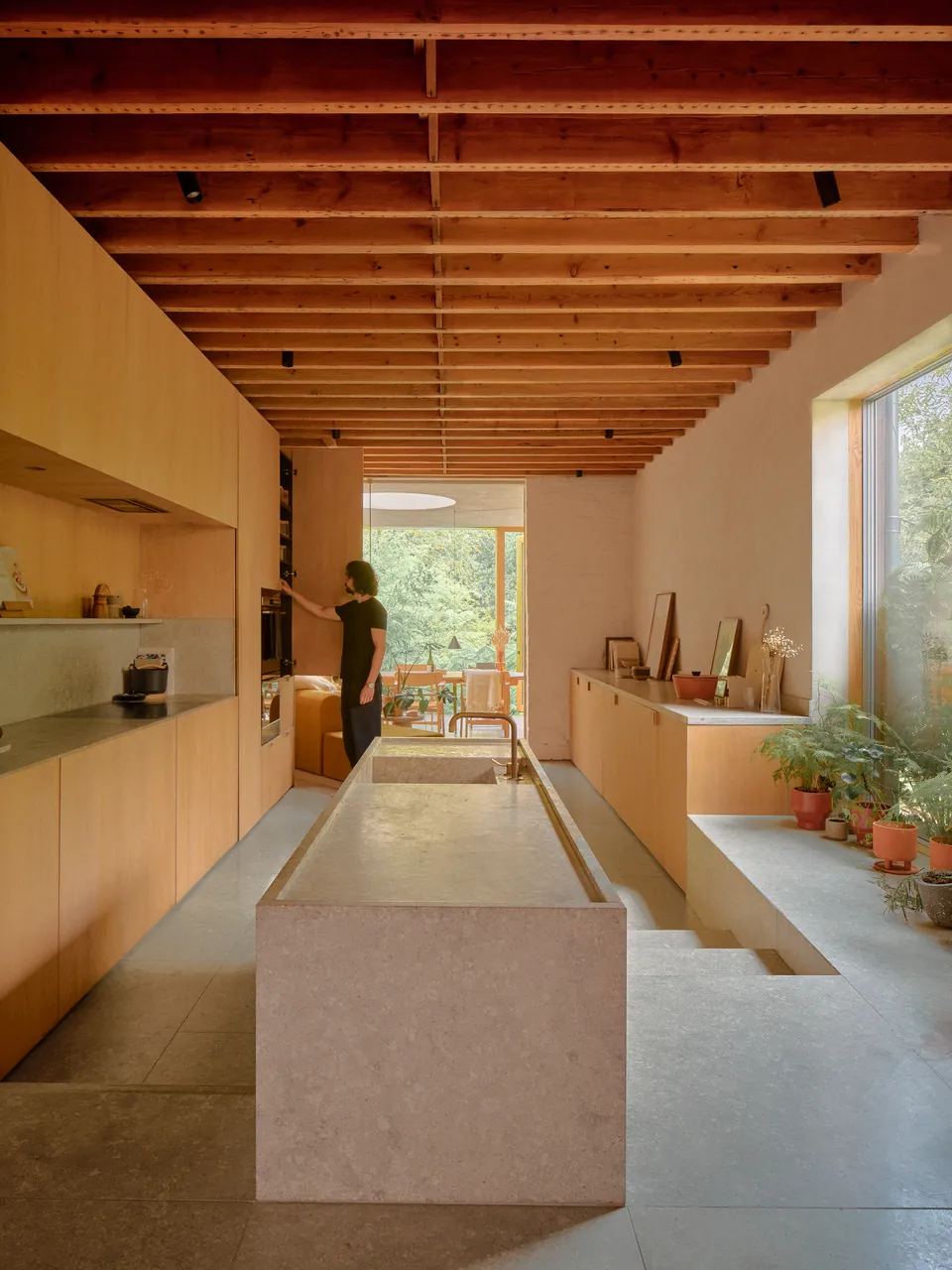 Long kitchen with a stone island beneath exposed timber joists
