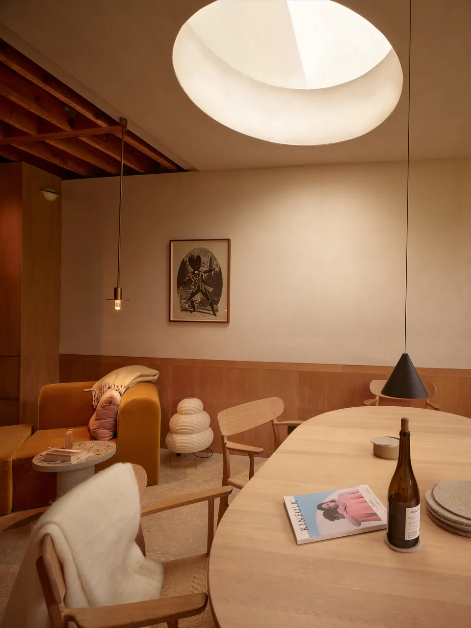 Round skylight above a dining table laid with wine and books