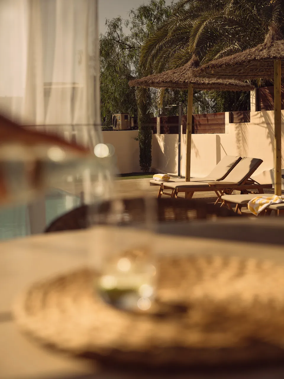 Glass tabletop in soft focus, loungers and parasols beyond
