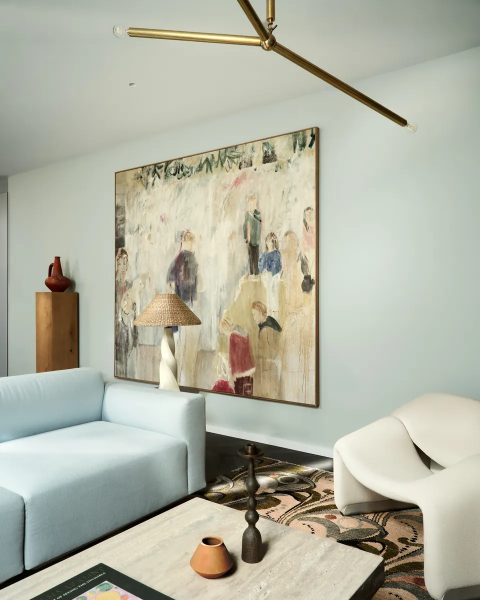 Living room with a pale blue sofa, sculptural chair and large painting