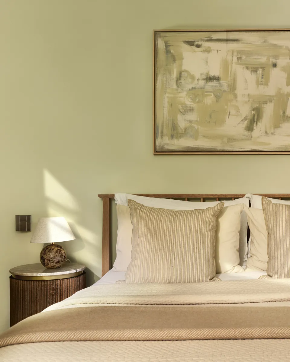 Bedroom with sage walls and a painted canvas above the bed