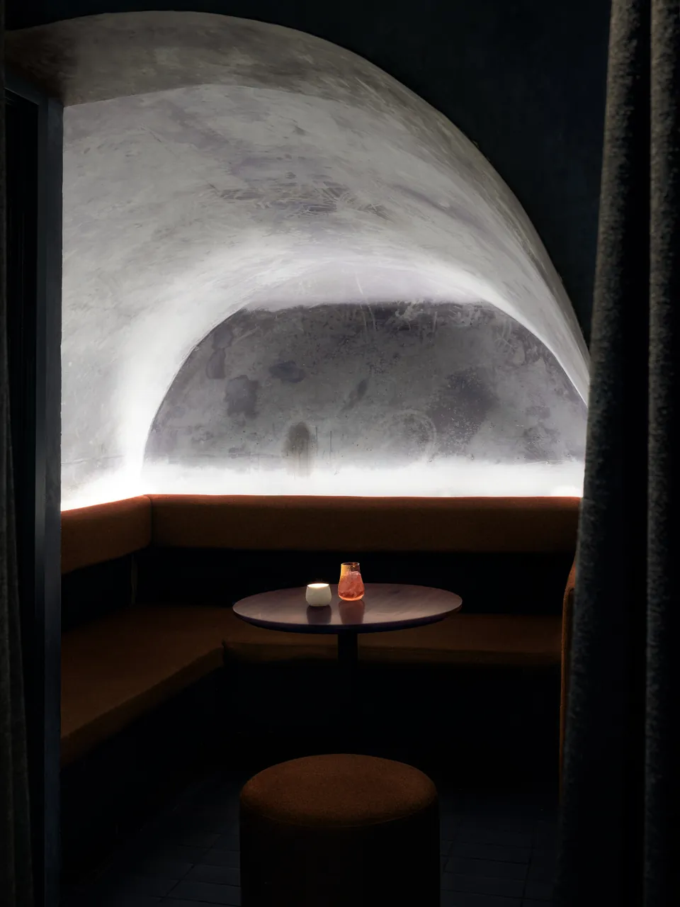 Vaulted booth lit from below, a single candle on the table