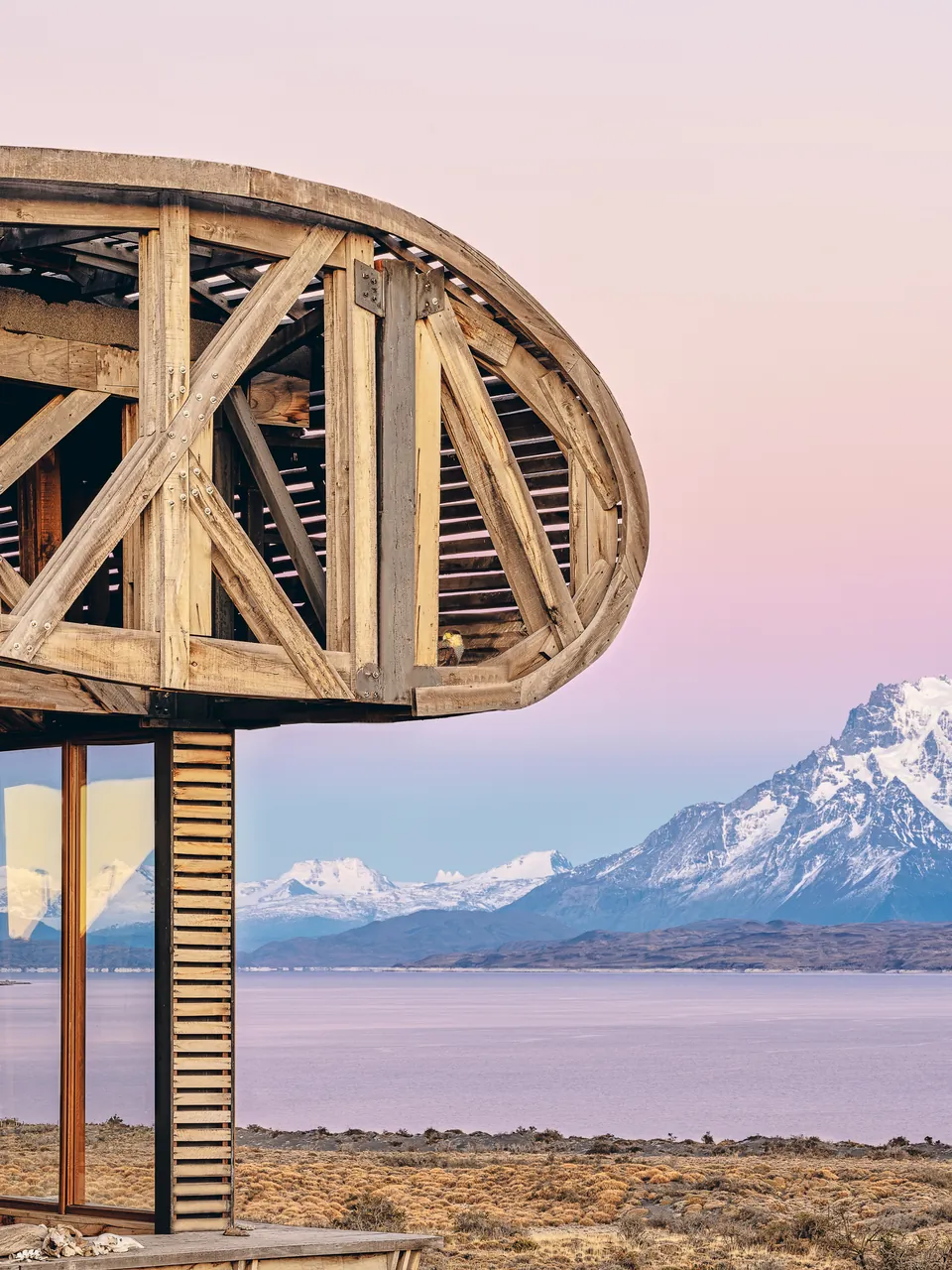 Timber frame against snow peaks in a pink sunset