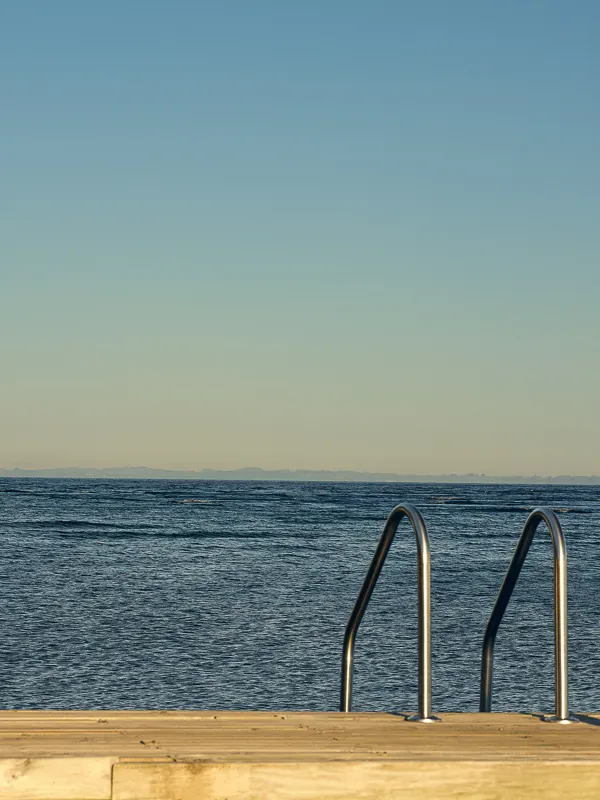 Pool ladder descending into open water