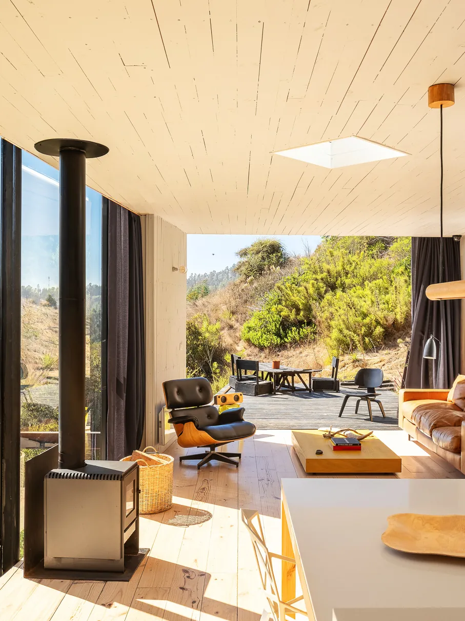 Open-plan living room with a stove, lounge chair and garden view
