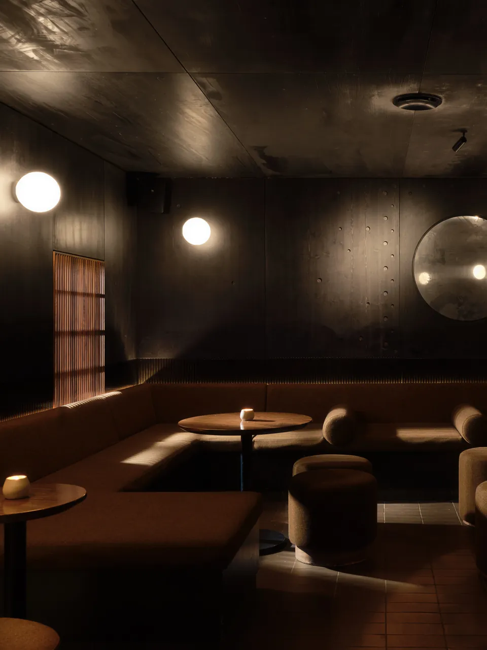 Dark lounge with round booths and glowing wall lights