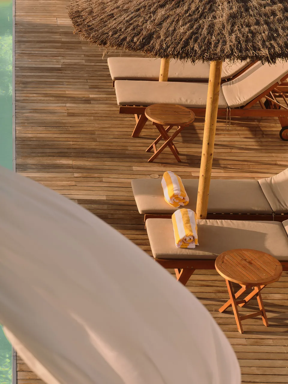 Pool loungers and parasols from above, linen in the foreground