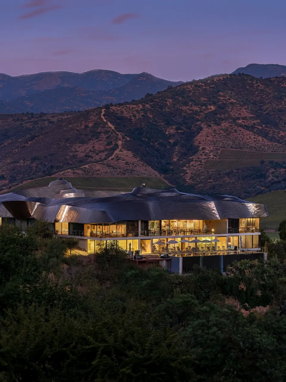 Hilltop hotel lit at dusk above the vineyards