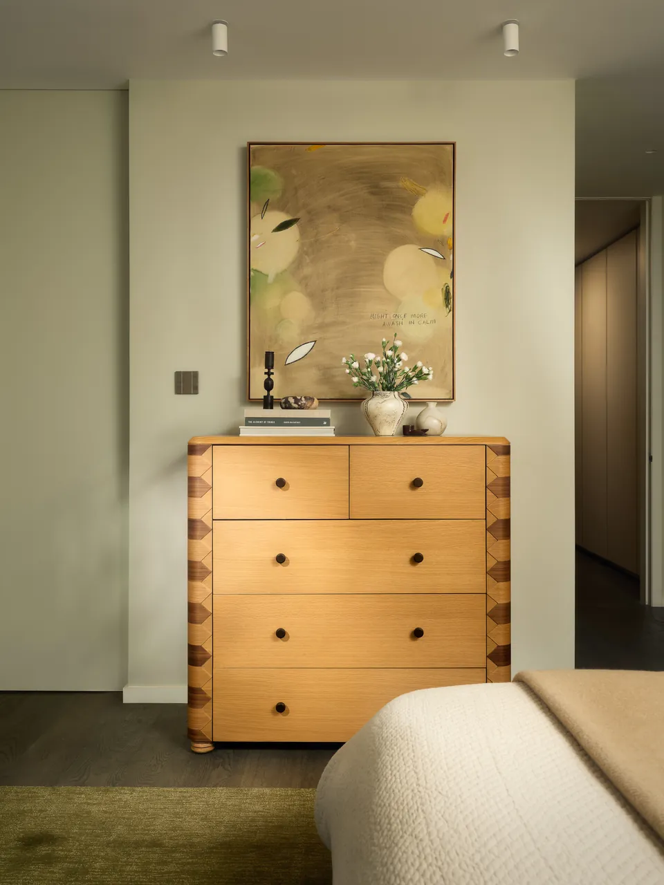 Timber chest of drawers beneath a painting