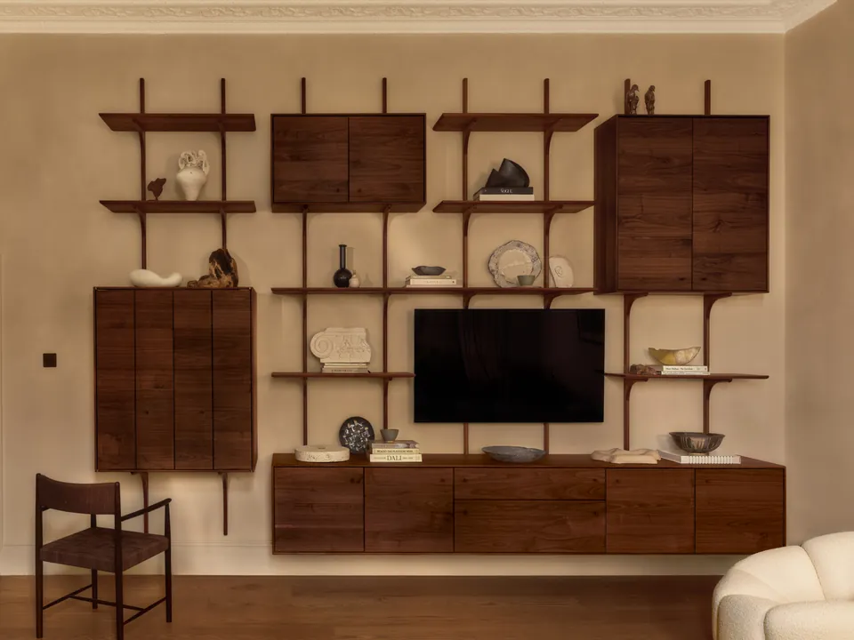 Walnut wall shelving and cabinets around a television, a chair beside it