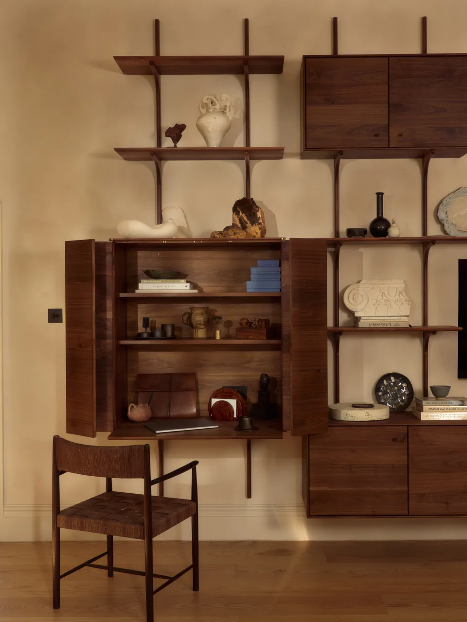 Walnut cabinet open on shelves of books and objects
