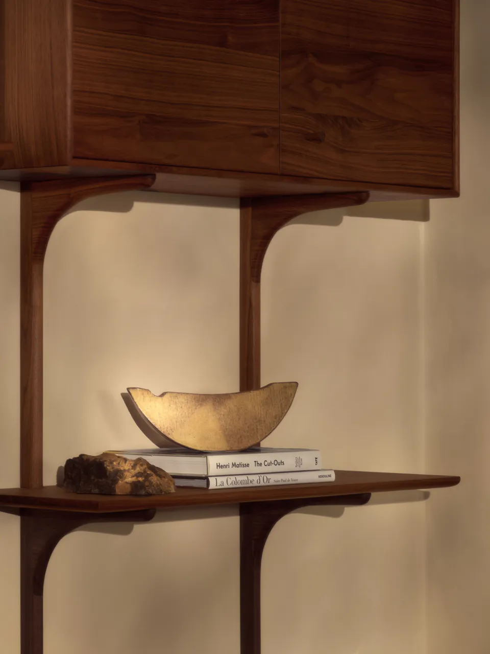 A brass bowl on a walnut shelf