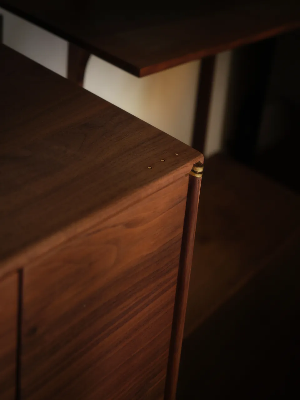 The corner of a walnut cabinet in low light