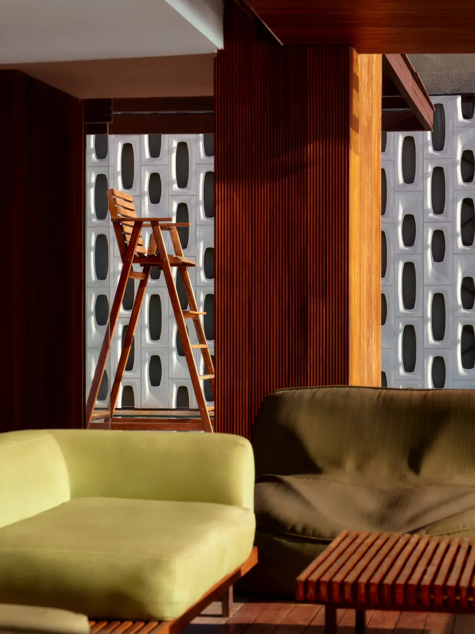 A lounge with green sofas behind a white perforated screen