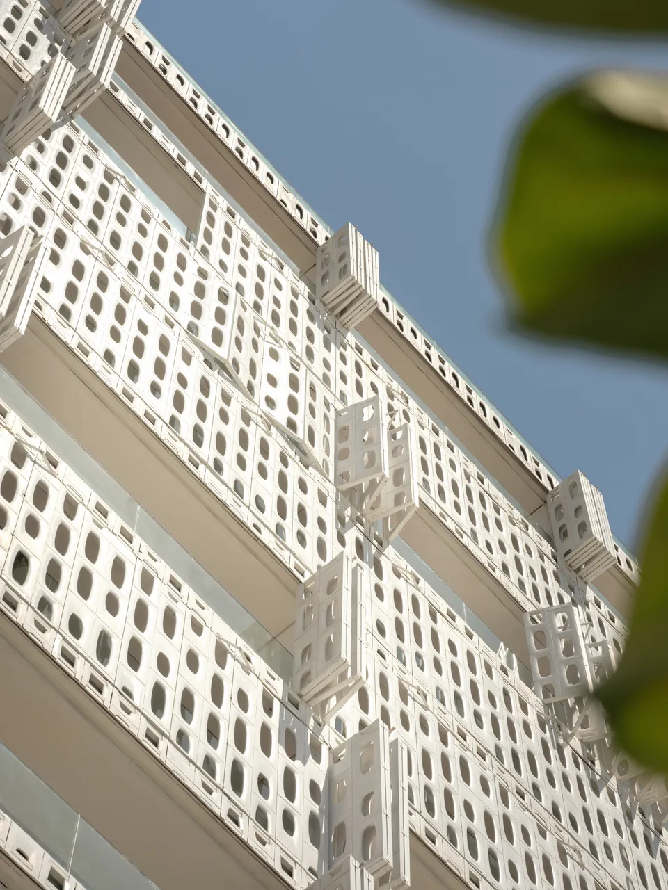 The perforated façade seen from below against a blue sky