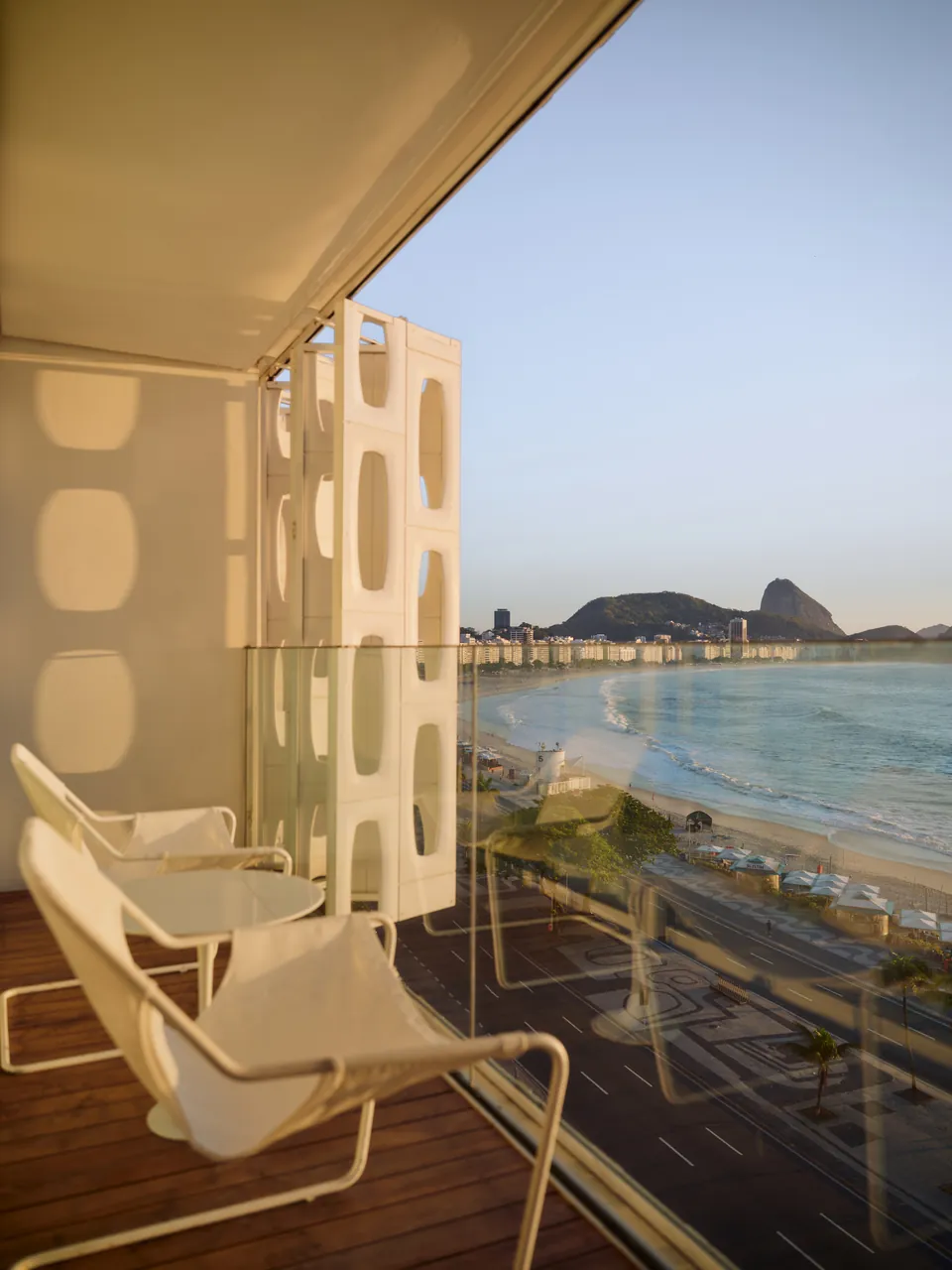 A balcony with white chairs above Copacabana beach