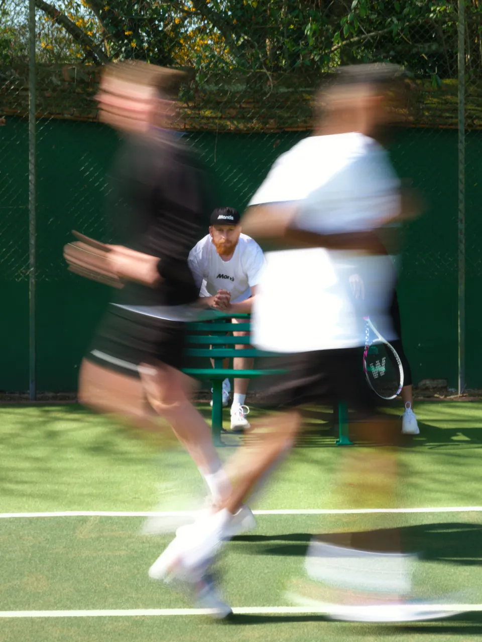 Two players running past in a blur on a grass court