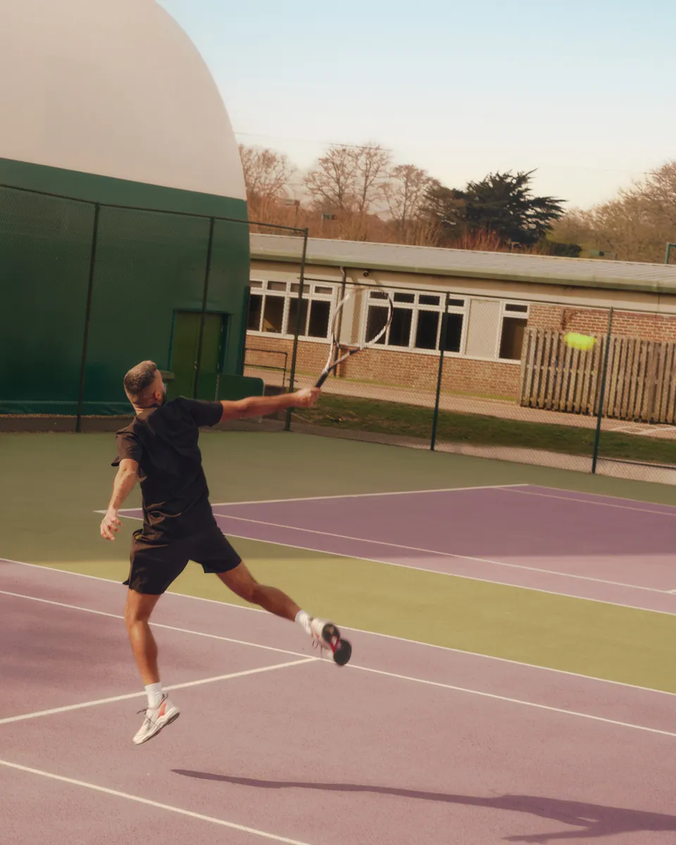 A player stretching for a forehand on a hard court