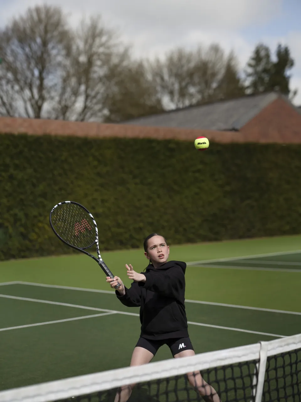 A child hitting a ball on a grass court