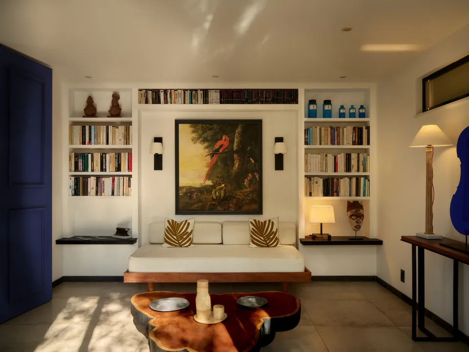 A living room with bookshelves, a painting and a carved wooden table