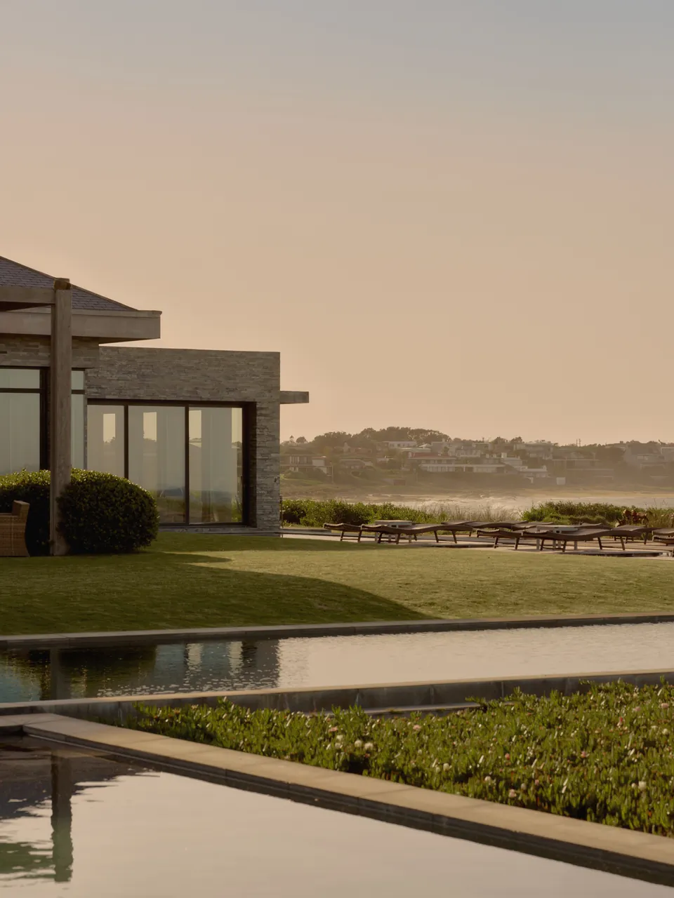 A low pavilion reflected in a still pool at dusk