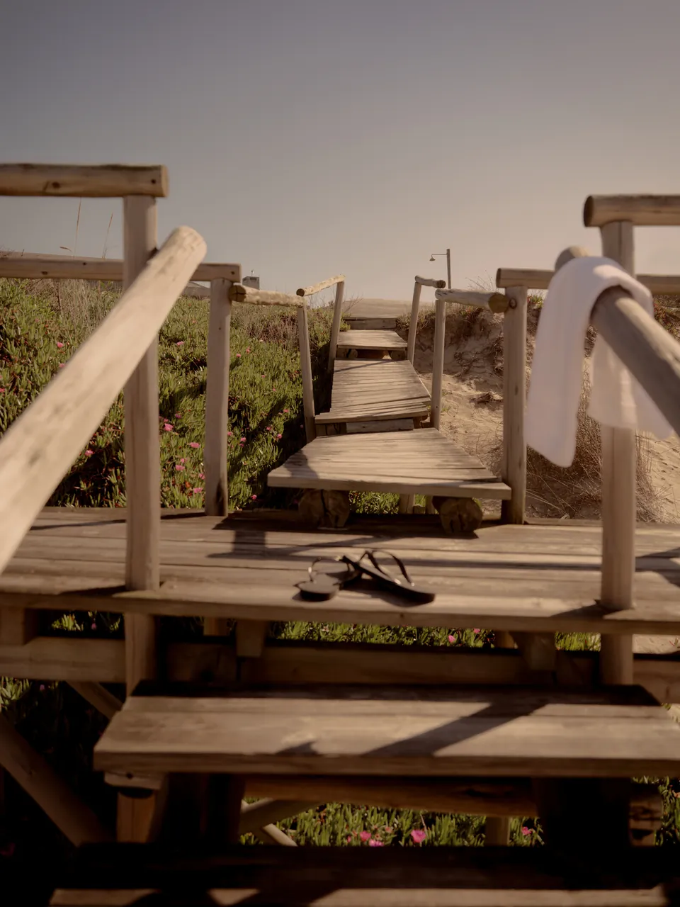 A timber boardwalk with a towel and sandals